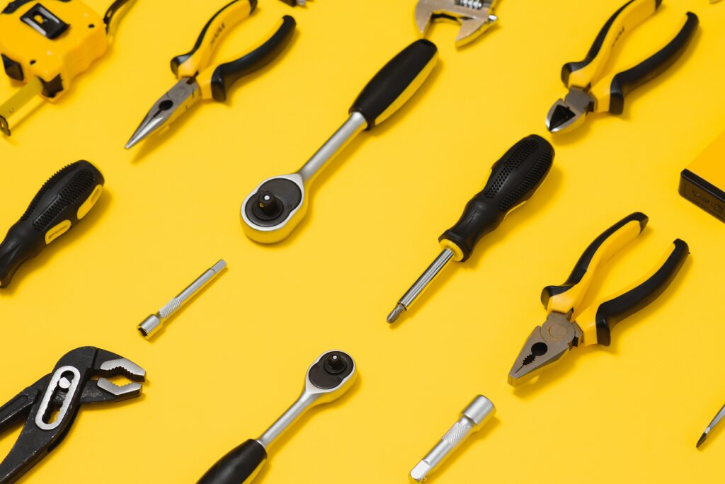 yellow and black handy tools (pilers and screwdriver) isolated on yellow background.
